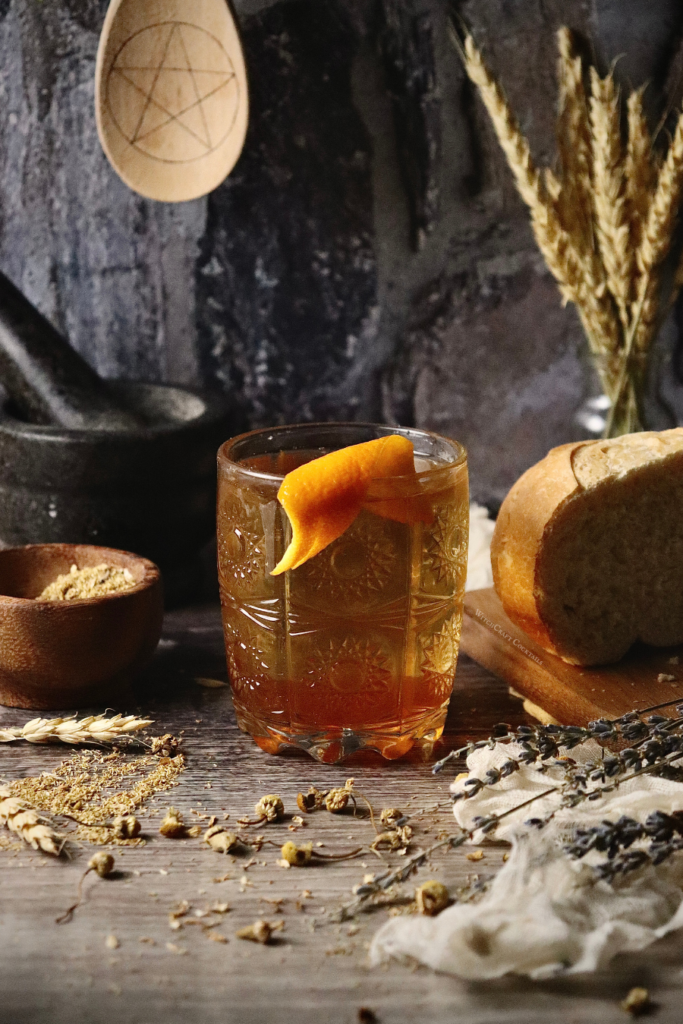 A honey and apple old fashioned in a glass with an orange peel spritz garnish