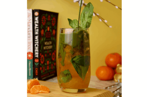 A matcha soda with orange mandarin juice on the bottom of the cup with green matcha pouring in from above.