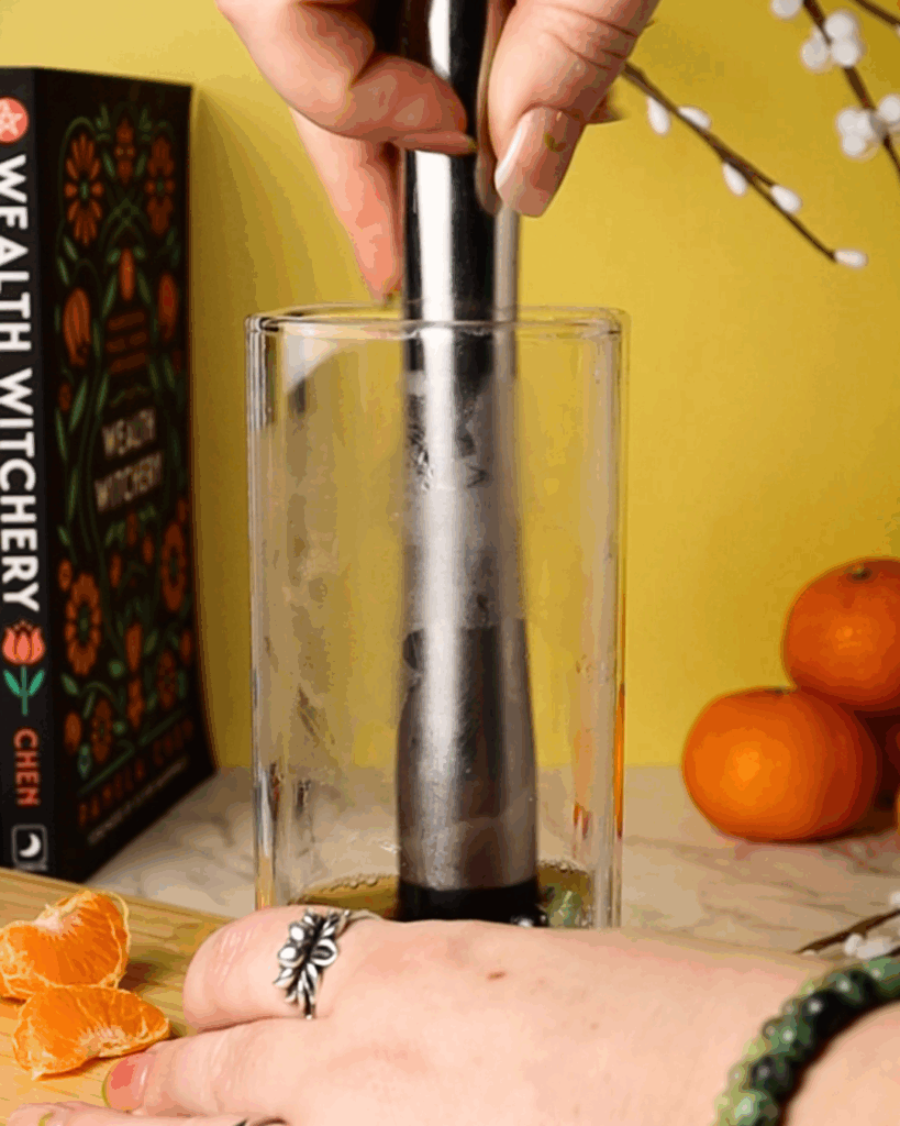 Basil, Honey, and chamomile being muddled in a tall glass.