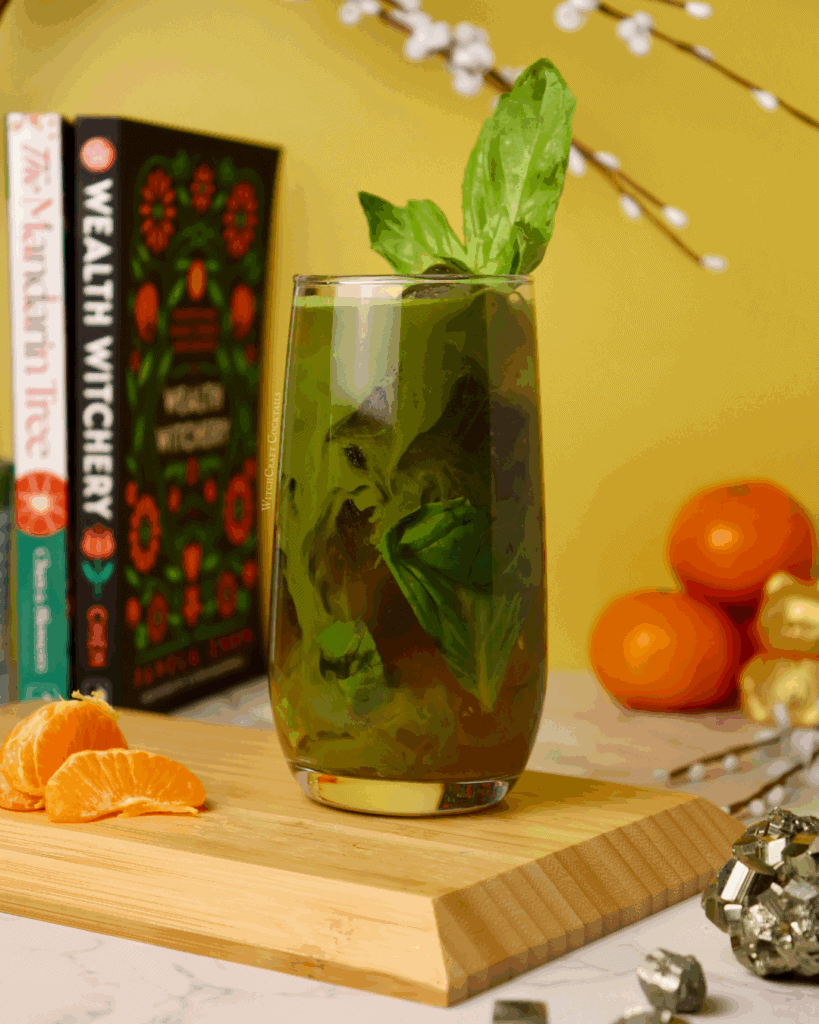 A refreshing matcha mocktail with basil, chamomile, and vibrant orange citrus, ideal for money manifestation rituals. This drink combines fresh ingredients with bold flavors for an enchanting mocktail experience.
