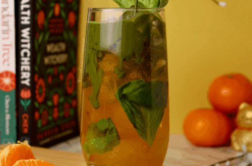 A matcha soda with orange mandarin juice on the bottom of the cup with green matcha pouring in from above.