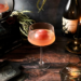 white wine sour with red ice cube sphere for the eclipse in a dark academia-themed backdrop